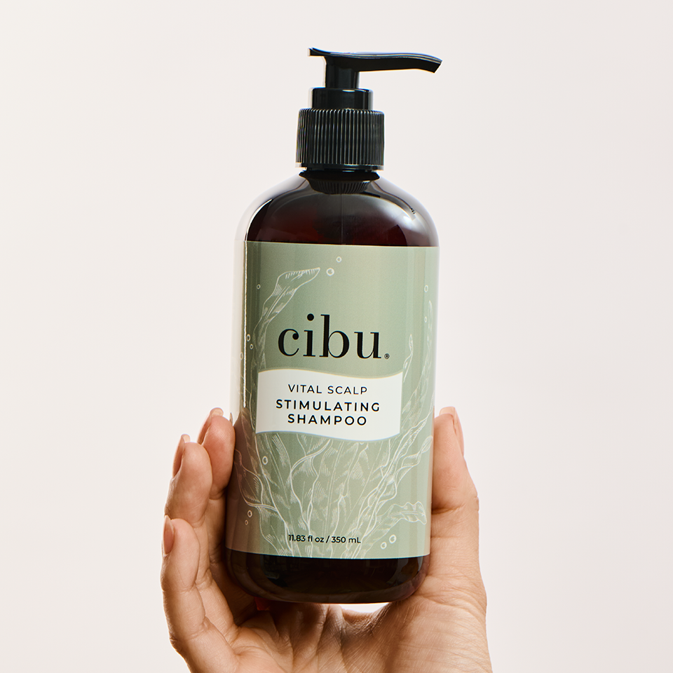 Hand holding a bottle of cibu shampoo against a light background